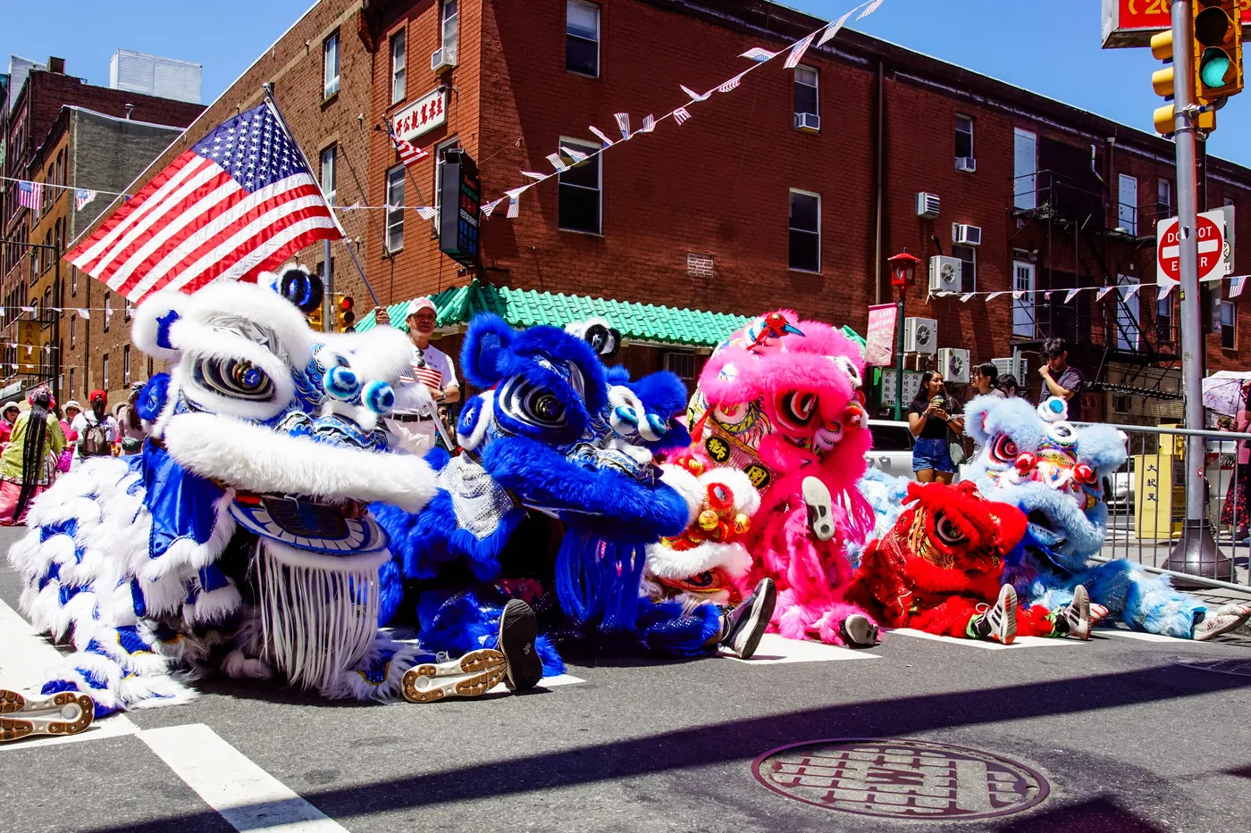 Blue, pink and red lions resting on a Chinatown street under an American flag