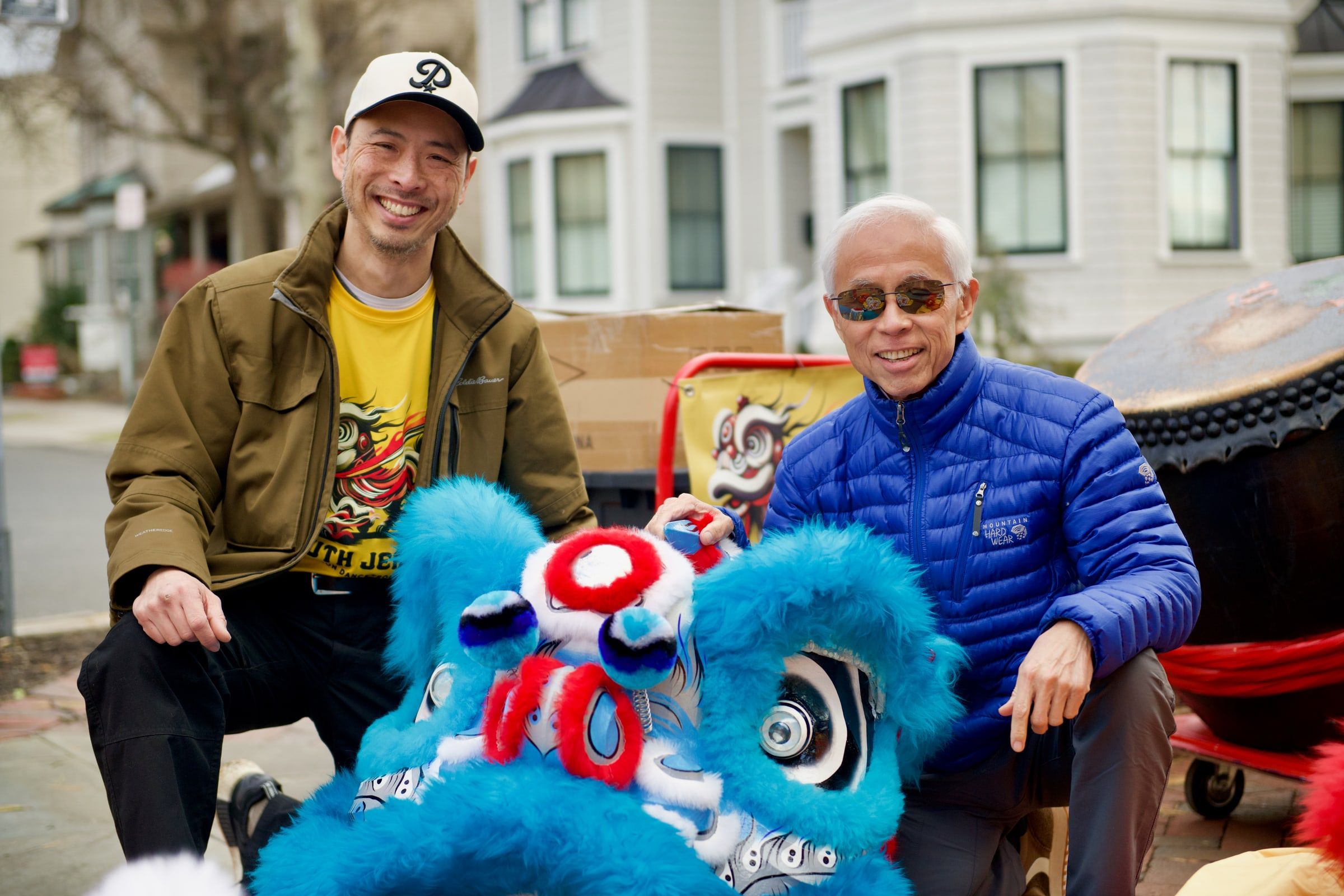 Two troupe leaders smiling beside a blue lion head and drum