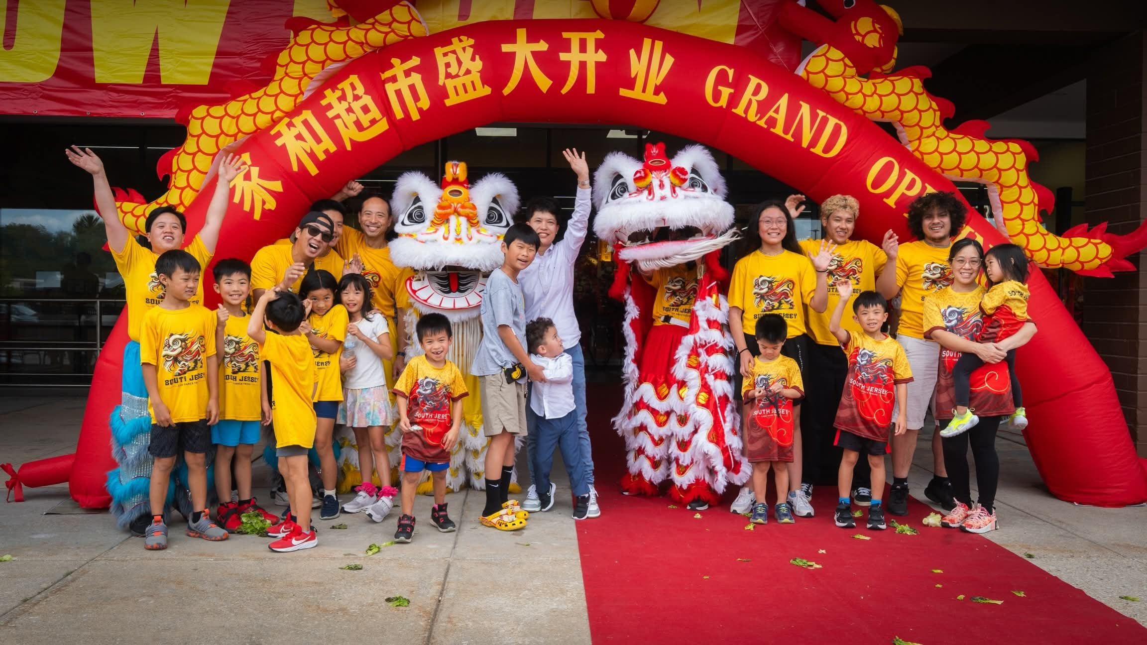 The troupe cheering under a red grand opening arch outside a supermarket