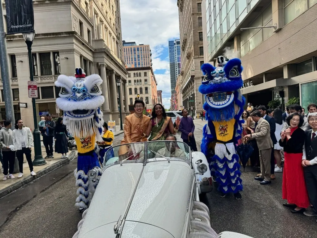 Two blue lions escorting a vintage convertible through a city parade
