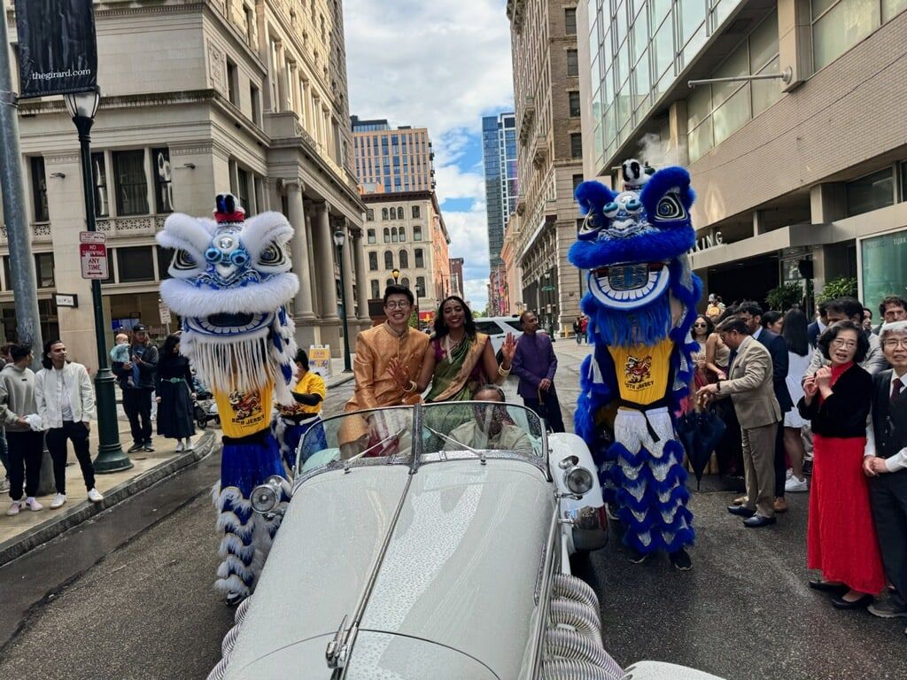 Two blue lions escorting a vintage convertible through a city parade