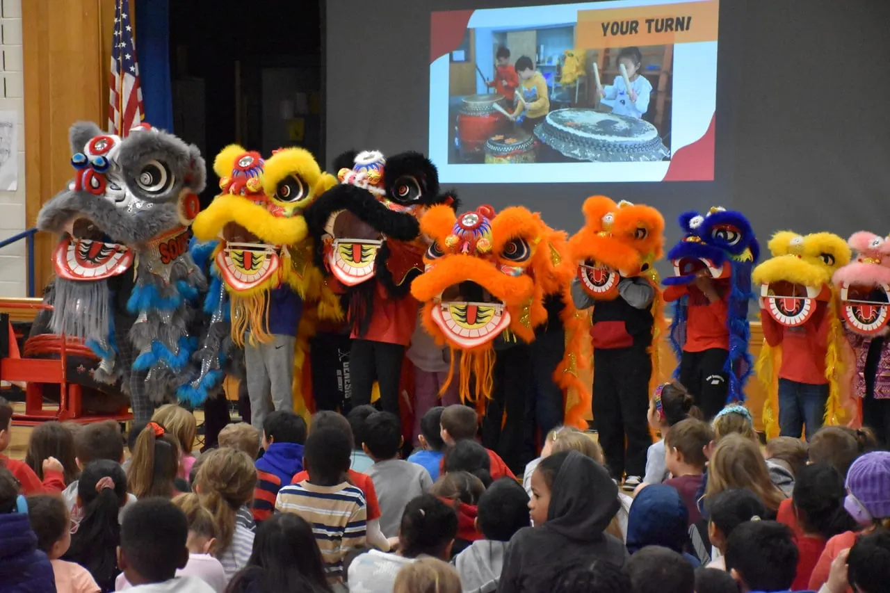 A row of colorful lions on stage in front of an elementary school audience