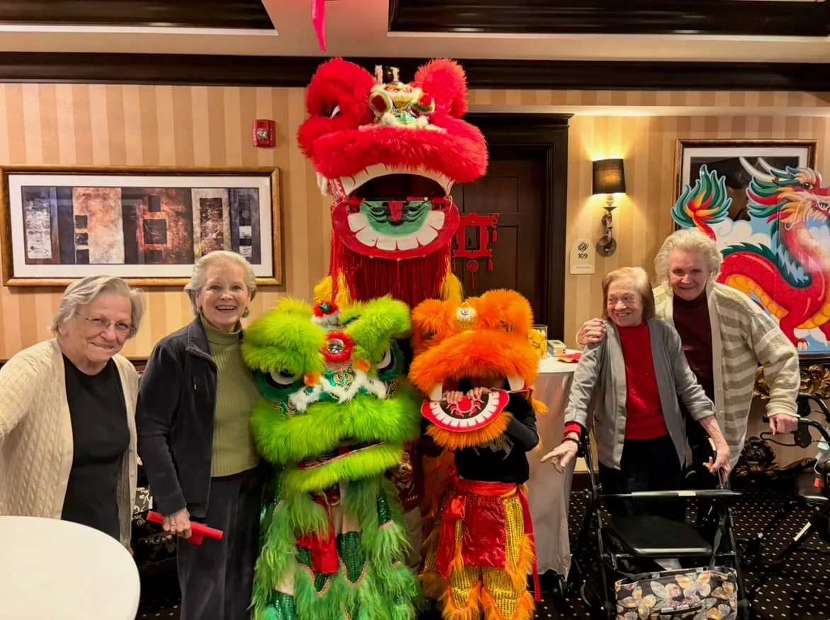 Residents of a senior center smiling alongside red, green and orange lions