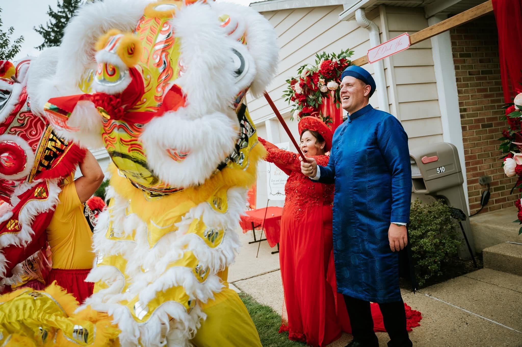 A yellow lion bowing to a couple in traditional wedding attire