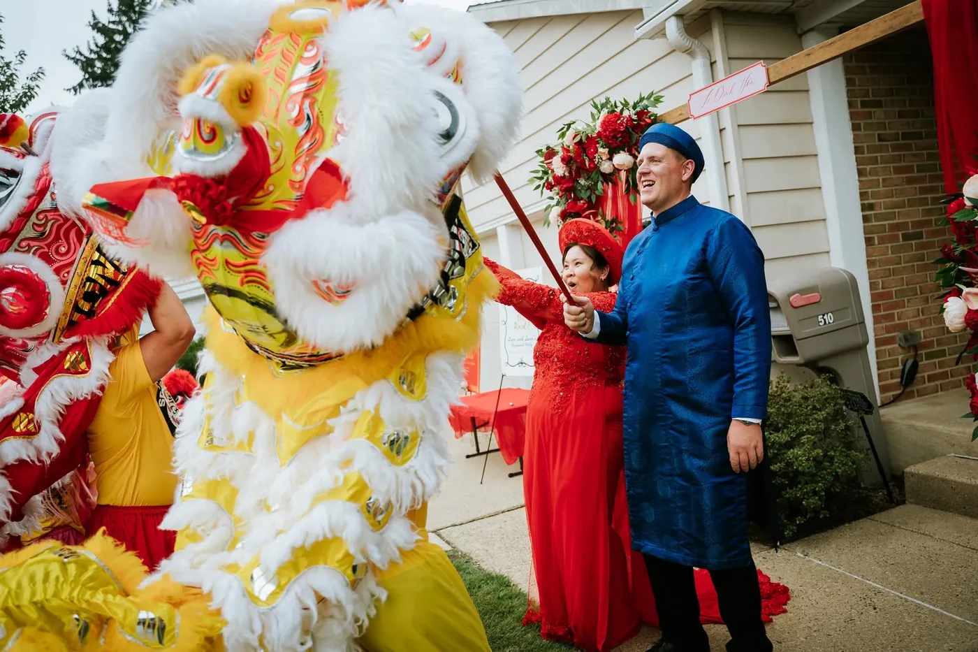 A yellow lion bowing to a couple in traditional wedding attire