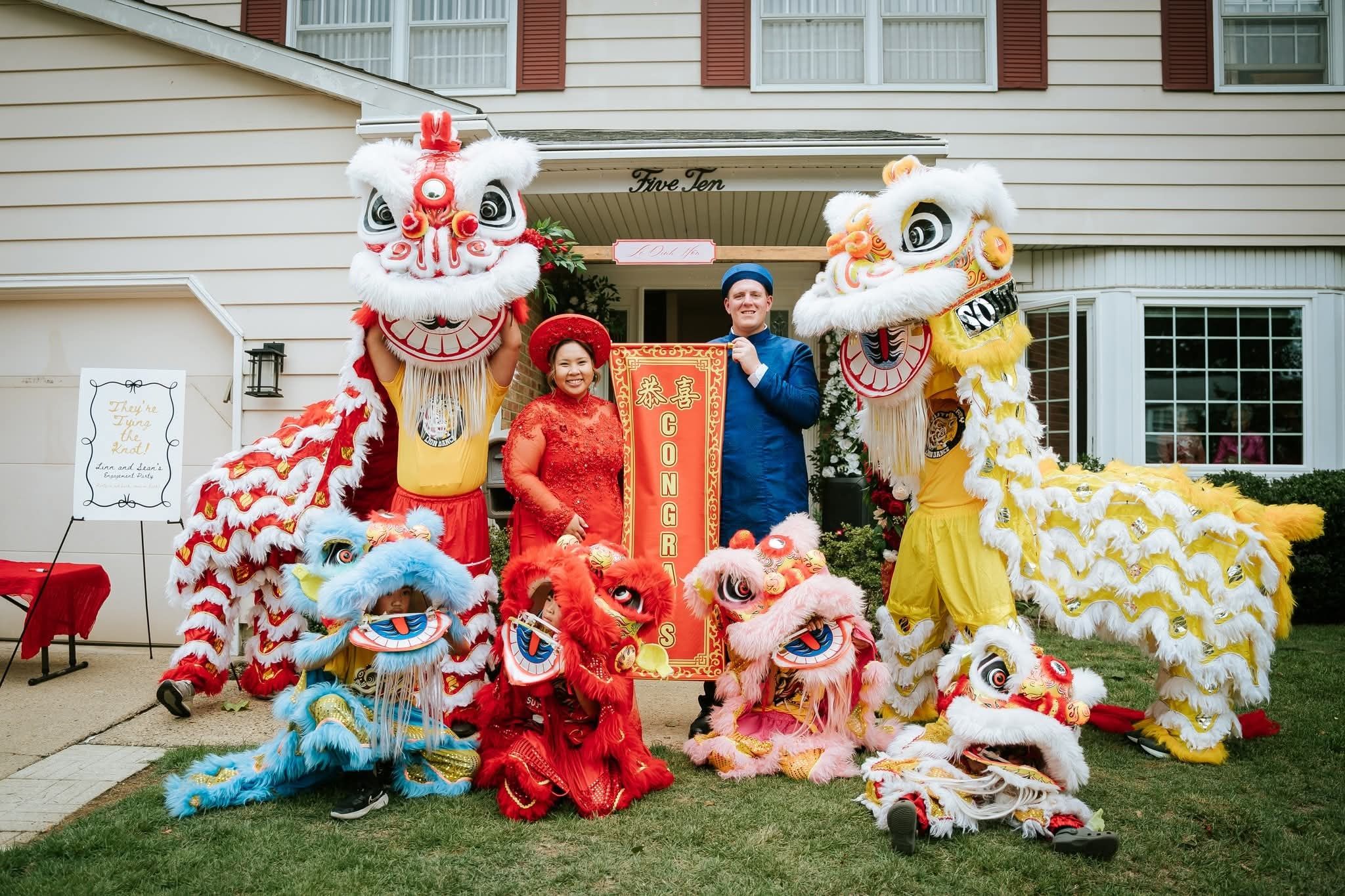 A wedding couple posing with the troupe's lions on a front lawn